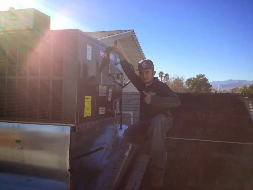 HVAC technician performing Air Duct Cleaning on a rooftop unit in Spring Grove