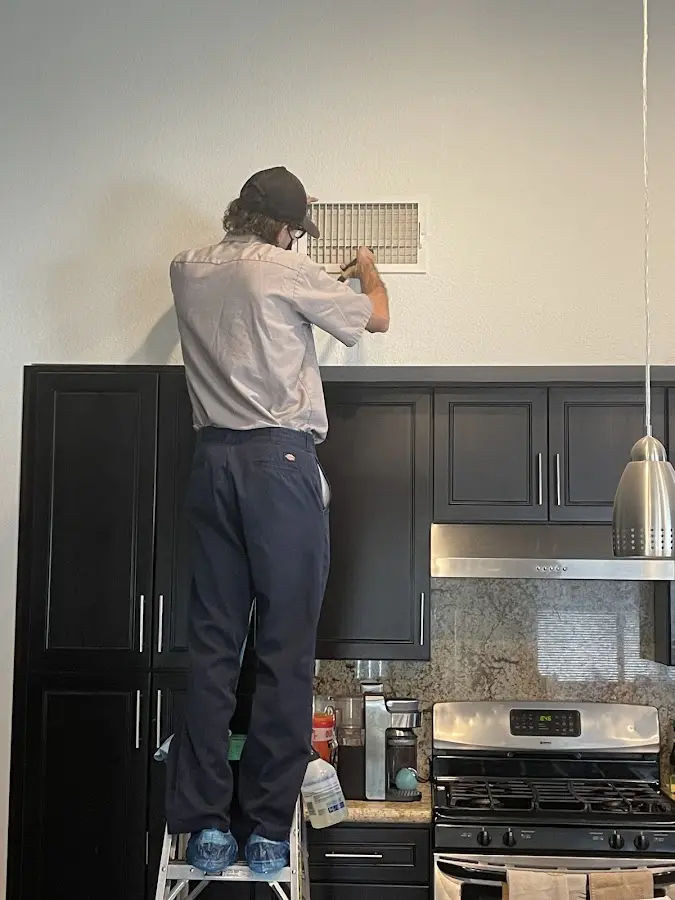 Technician inspecting an air vent during HVAC service in Spring Grove